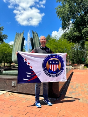 Dr. Josh Brunty holding the US Cyber Games flag. 